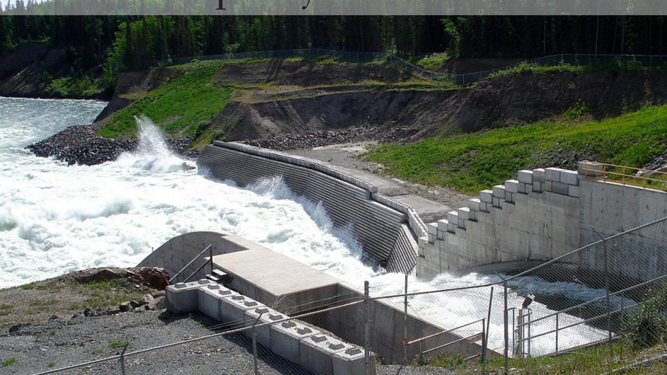 Skins Lake Spillway with rushing water and concrete infrastructure surrounded by forest.