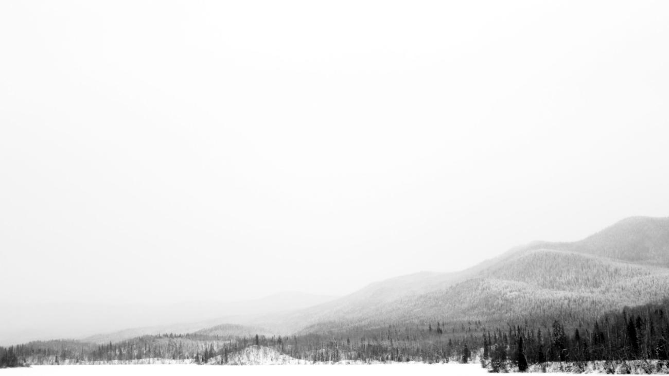 Glowing sunset over lake with dramatic clouds and silhouetted rocks in foreground.