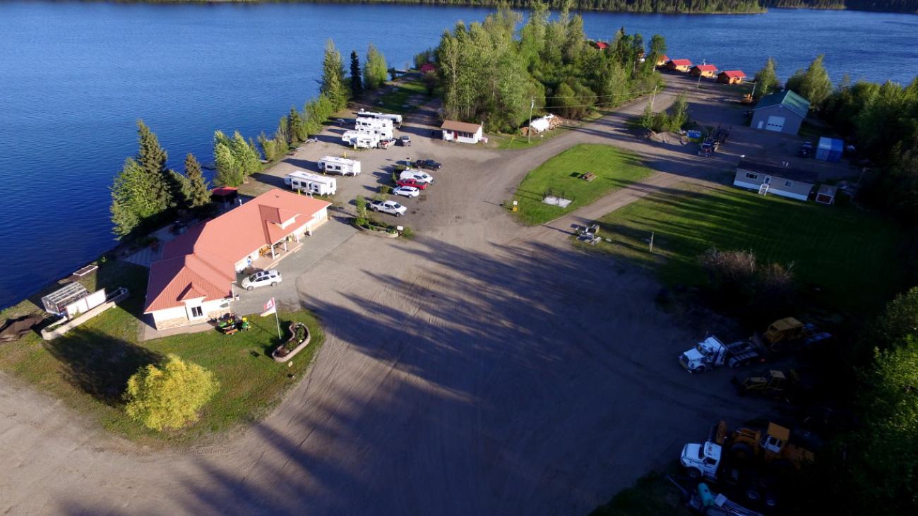 Aerial view of lakeside area with buildings, road, and trees.