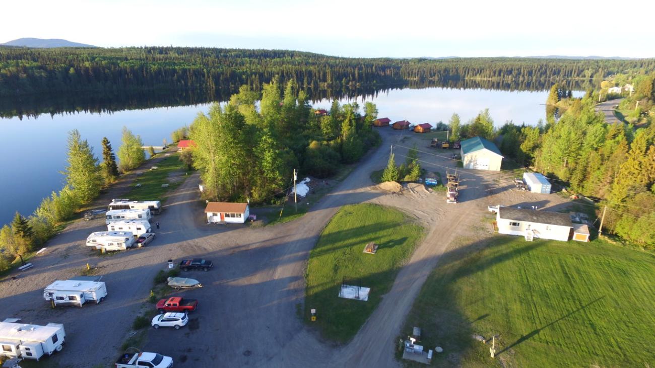 Lakeside RV park with trees, blue lake, and parked campers.