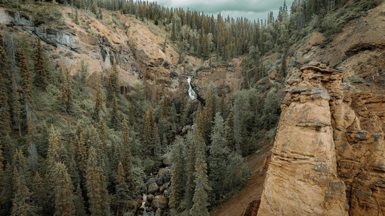 Panoramic view of Nourse Creek Falls craggy hills. There are small water rapids cutting through the rocky crag.