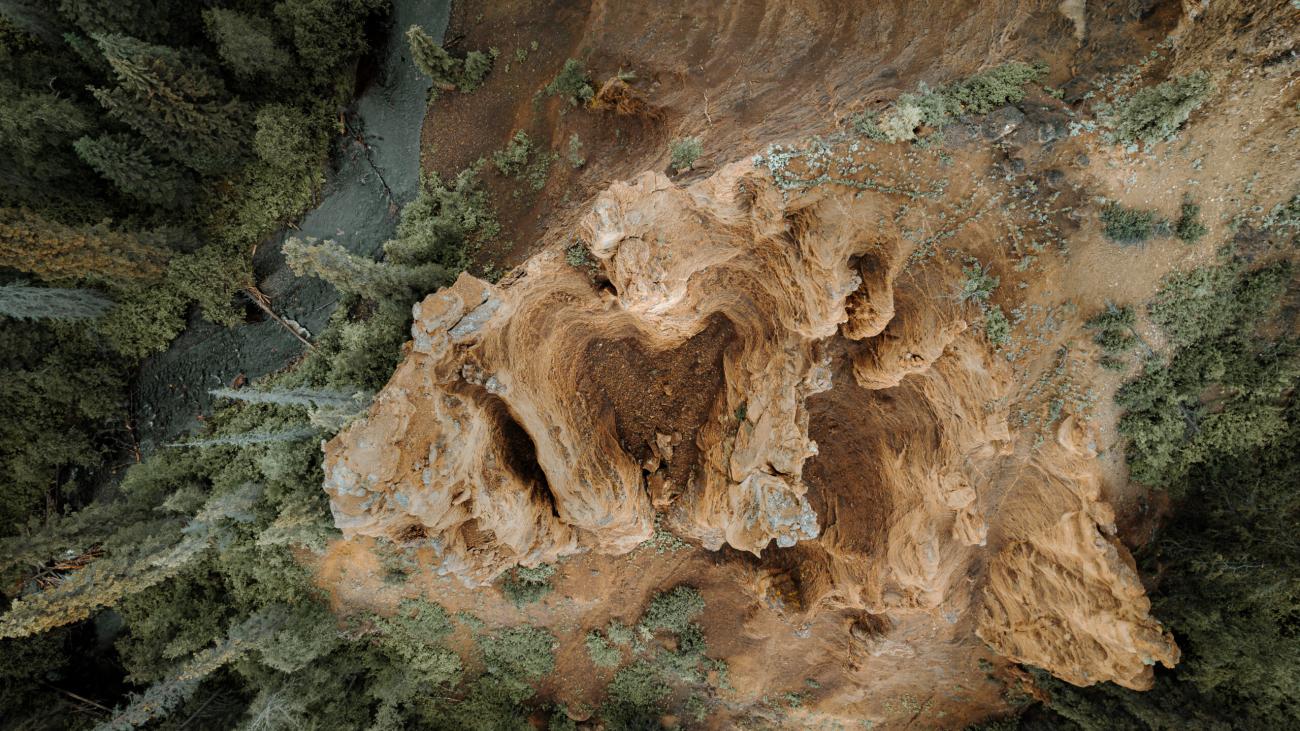 Aerial view of rocky crags. The rocky crag is surrounded by trees.
