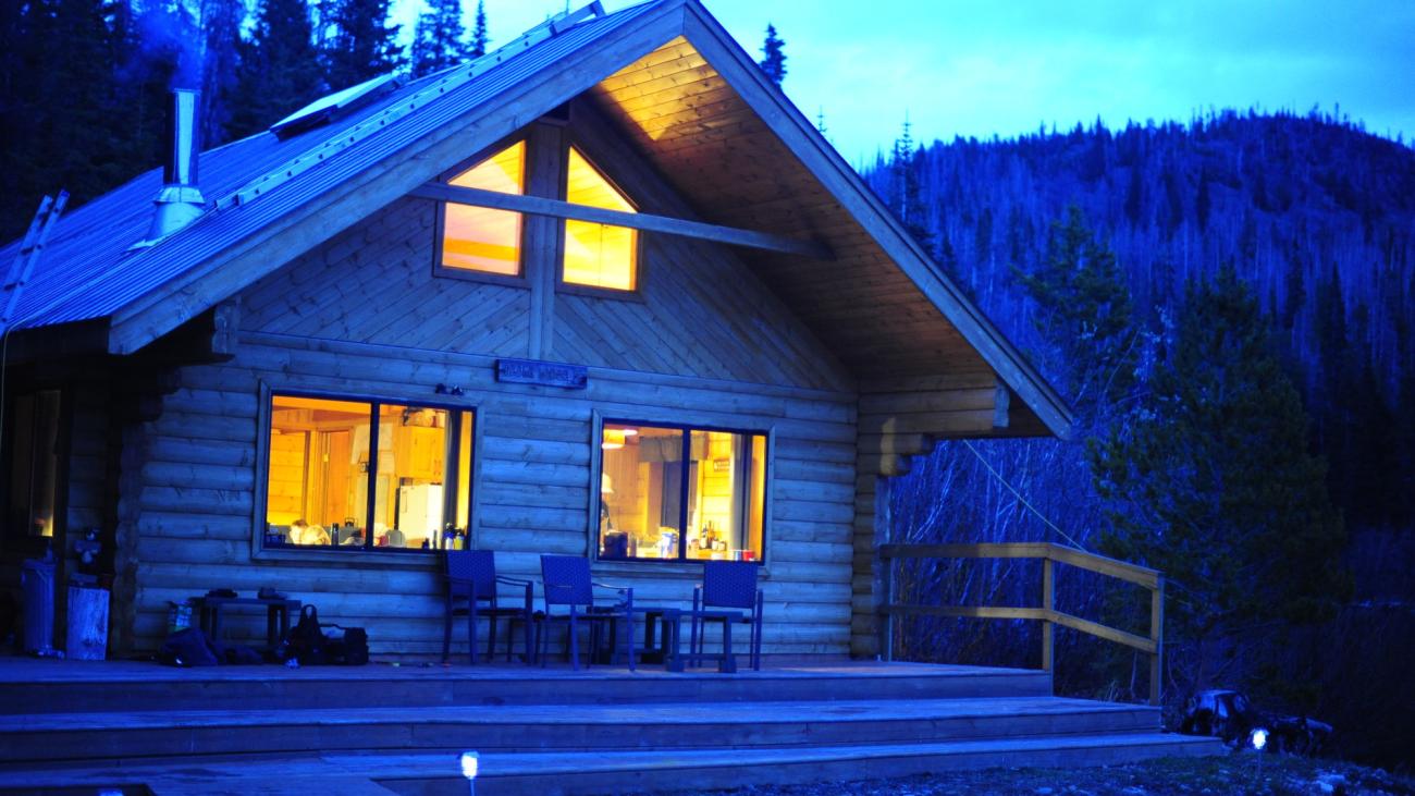 Cozy log cabin with glowing windows at dusk.
