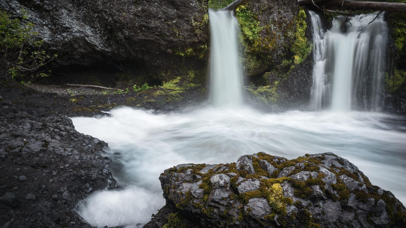 Waterfalls near rocky cave.