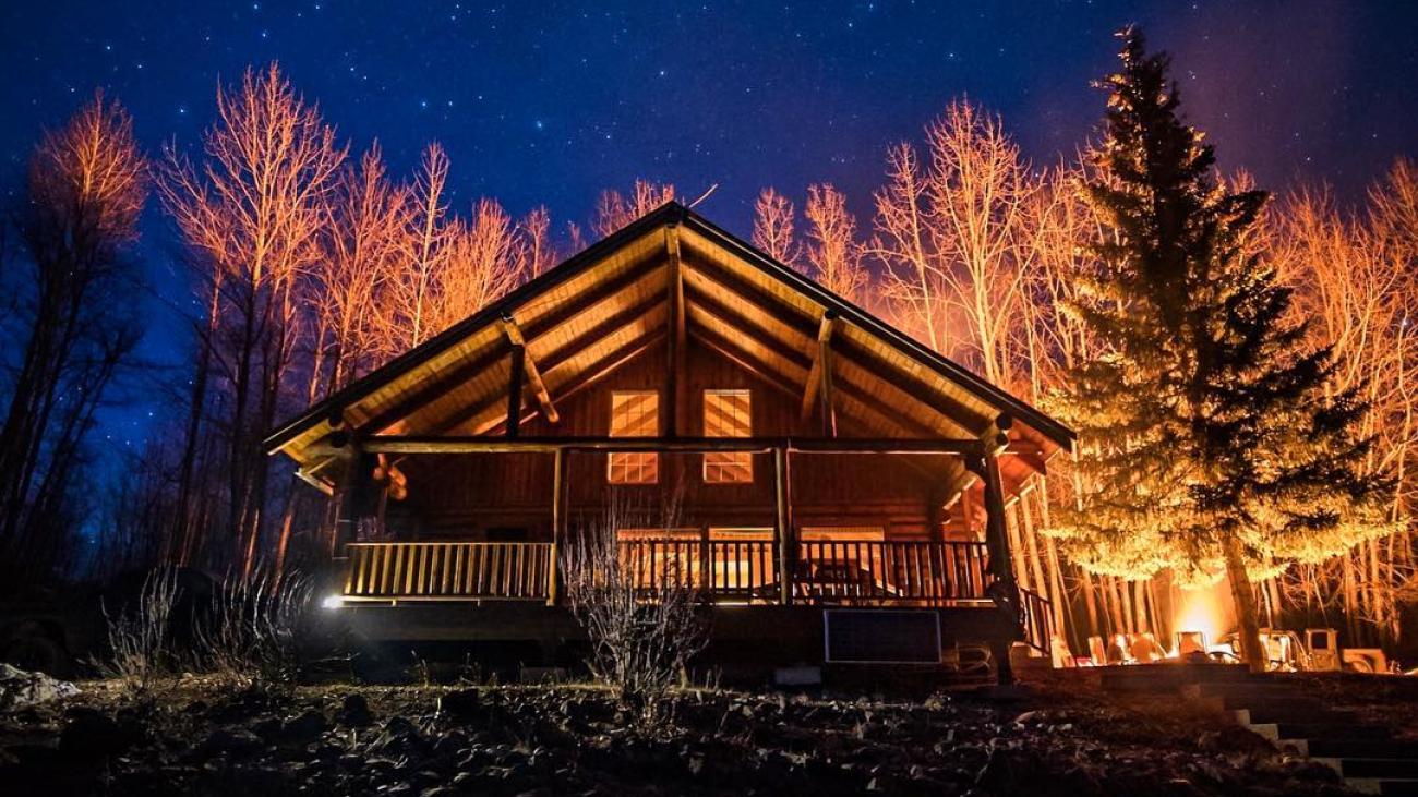 Serene twilight view over still lake with soft mountain reflections and bare trees.