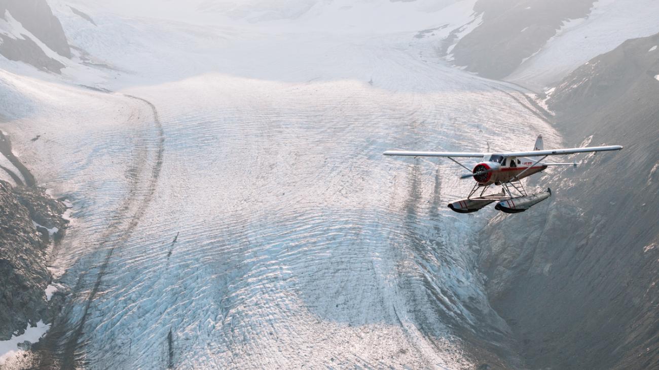 Seaplane flying over a snowy mountainous area.