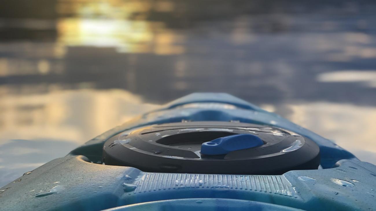Blue kayak on lake. The sun is setting in the background.