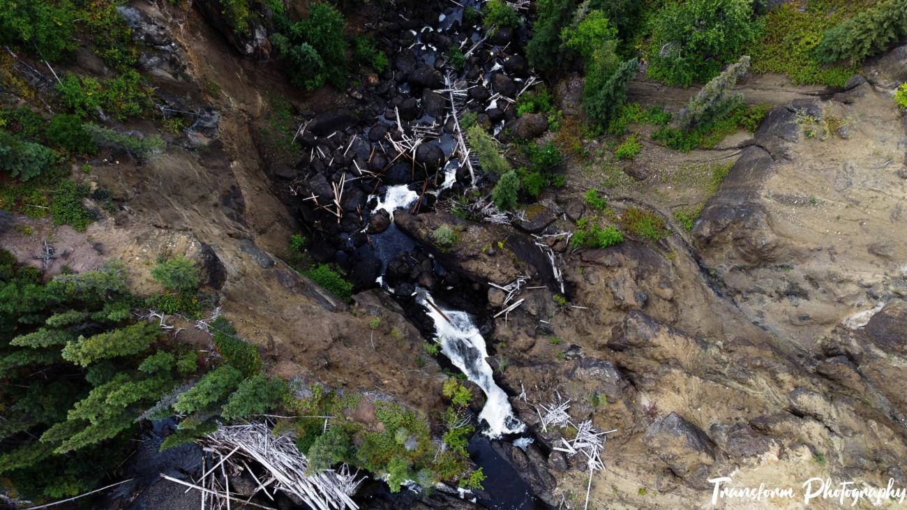 Aerial view of creek flanked by rock cliffs.